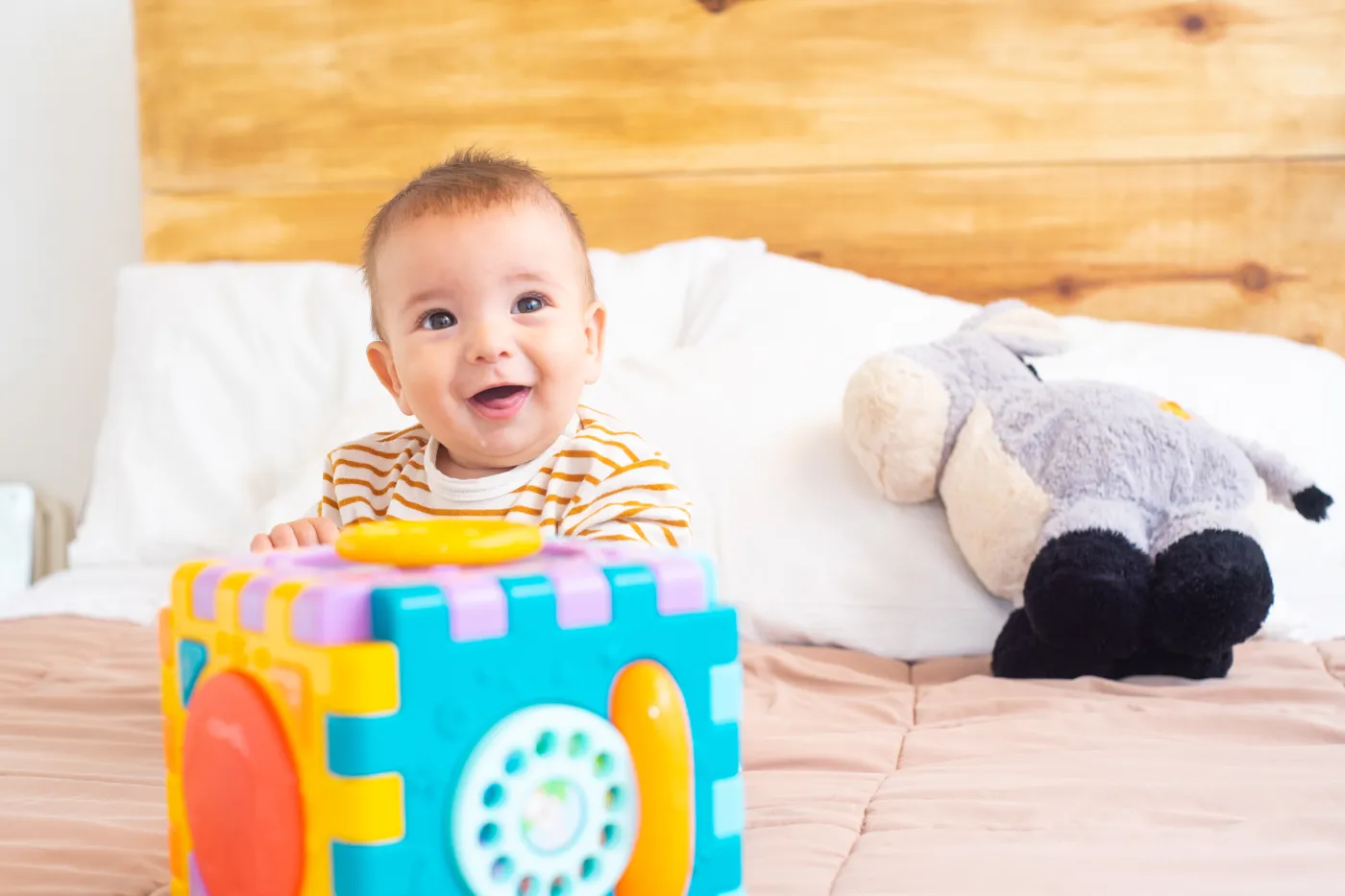 closeup shot cute happy baby playing with toy bed